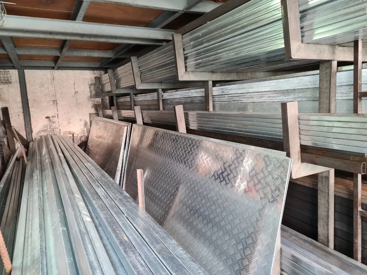 Racks of galvanised tubes and checkered steel sheets at Quincaillerie Gaffoor